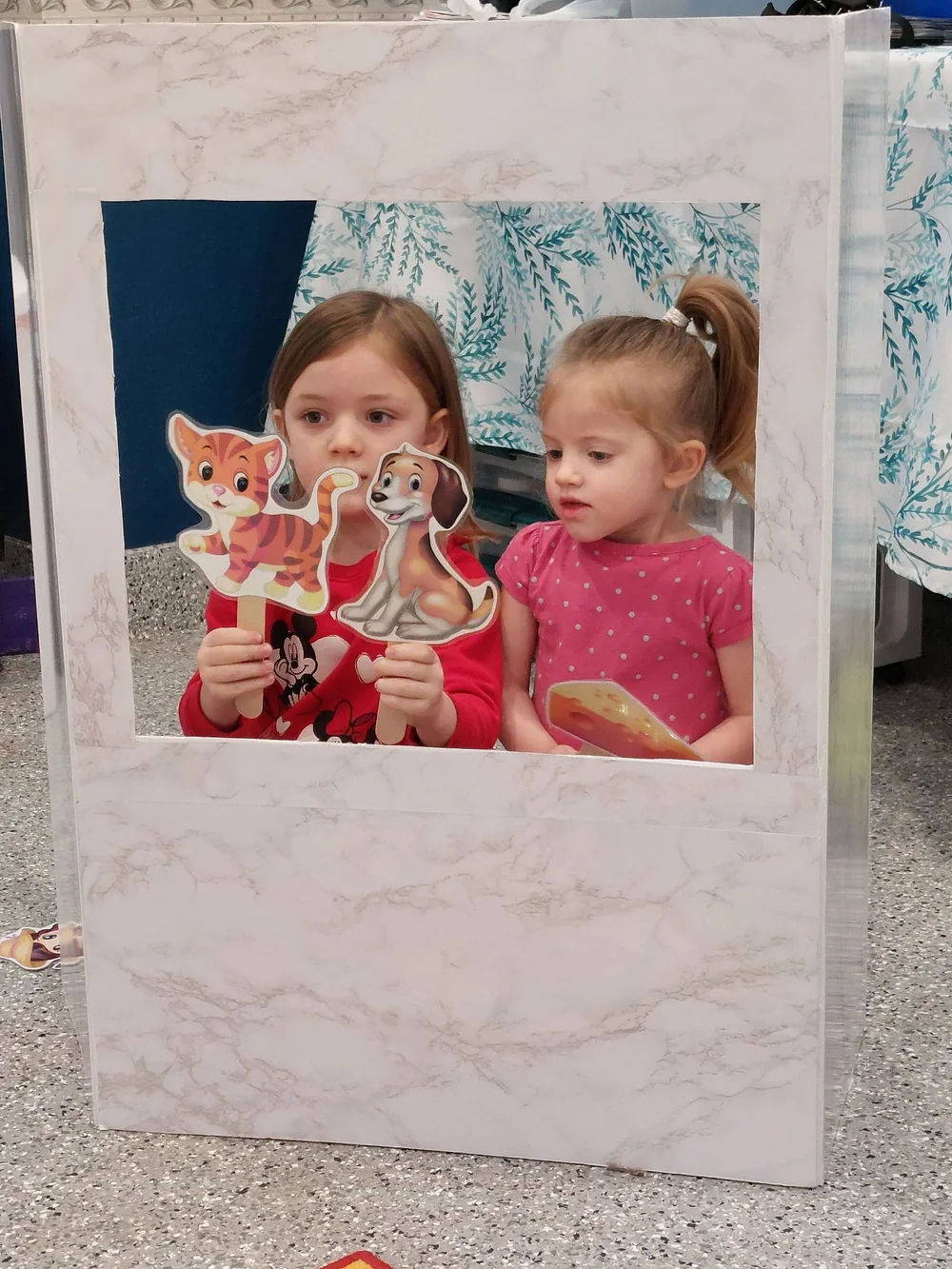 Two girls performing with cat and dog puppets in a puppet theatre