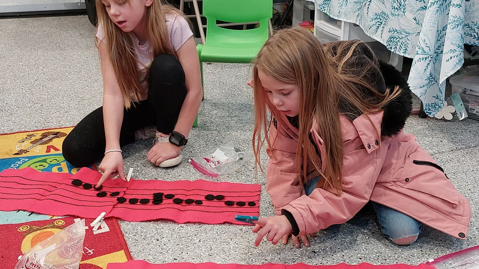 Two girls building rhythms with large notation cards on the floor