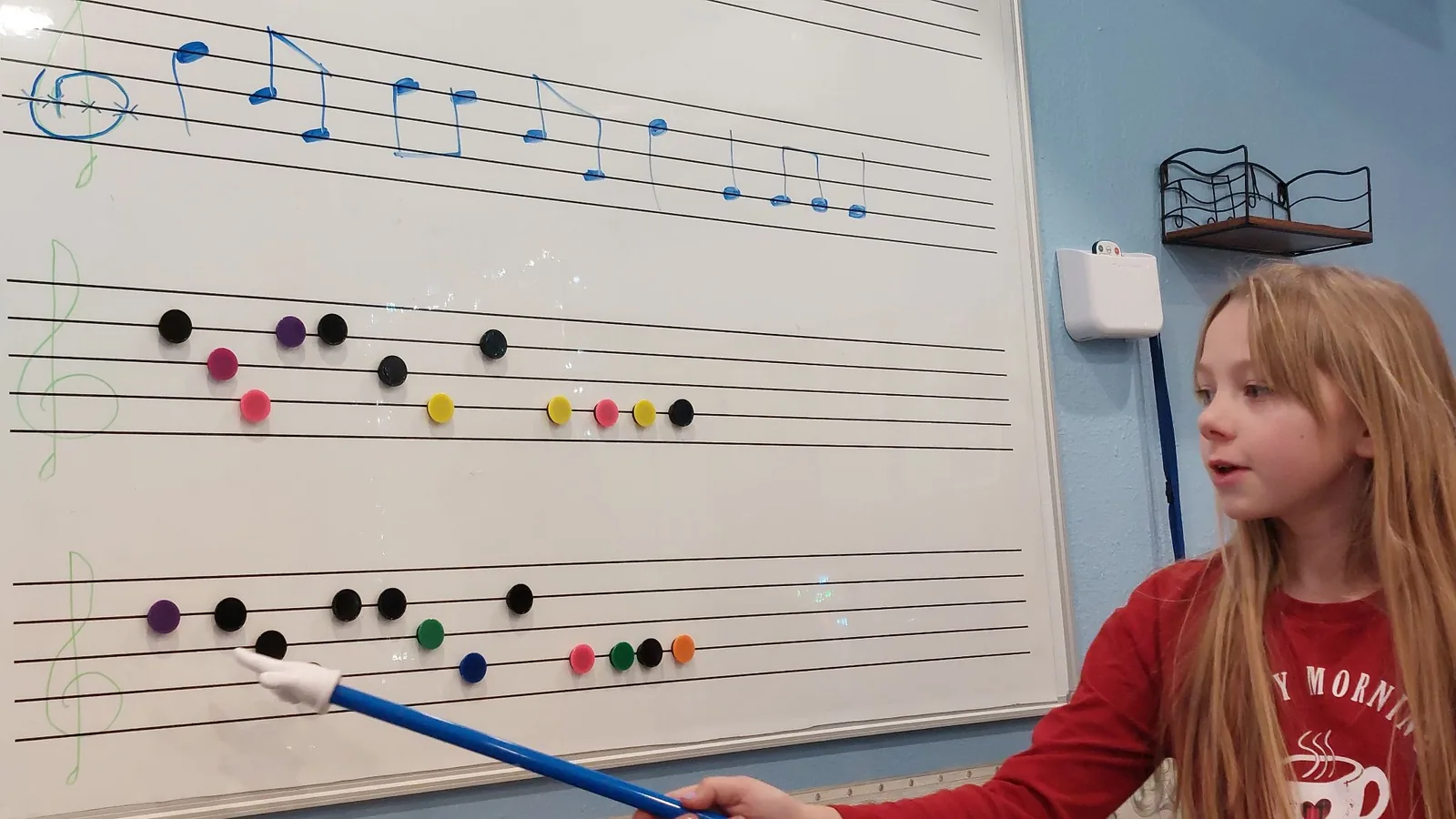 A girl placing notes on a large magnetic music staff