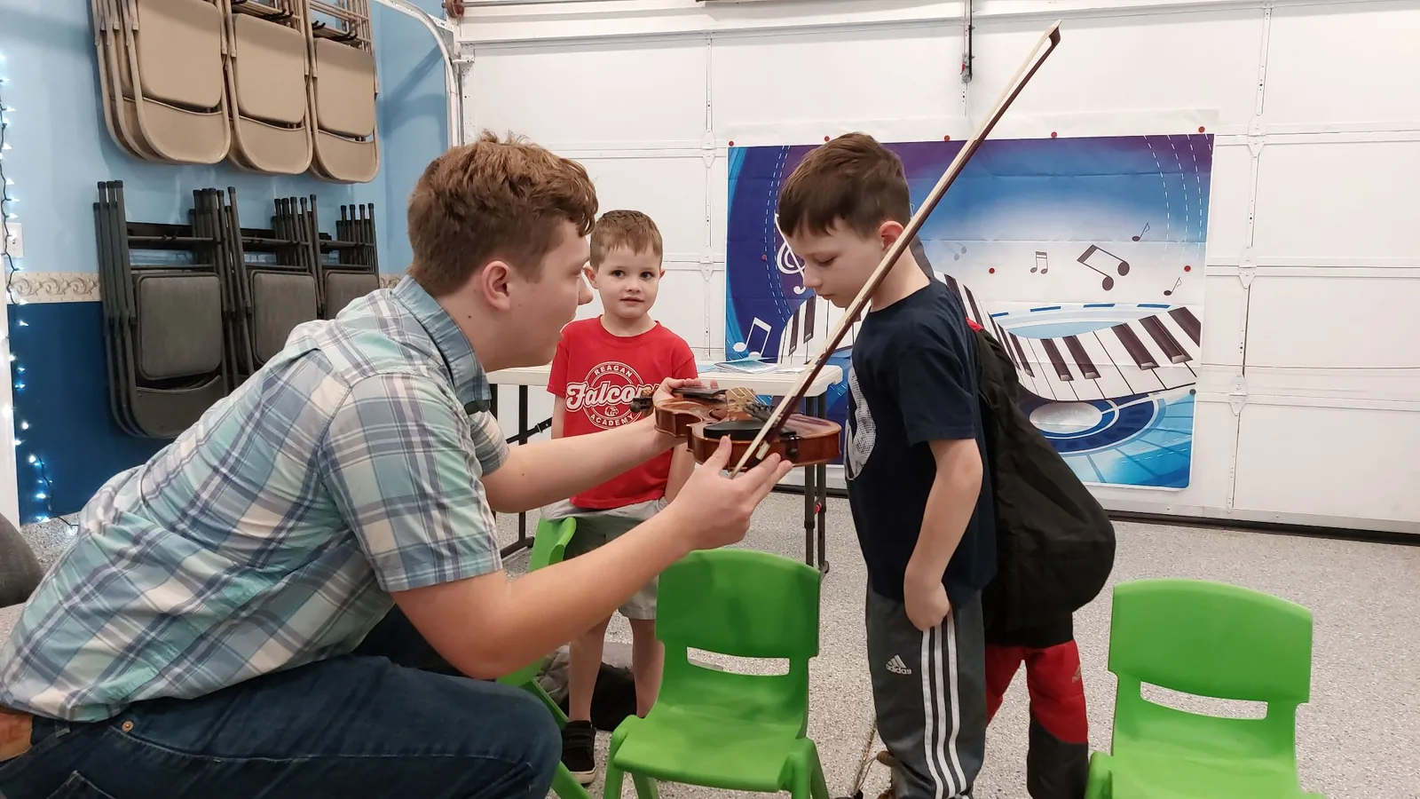A teacher showing young students how to hold a violin